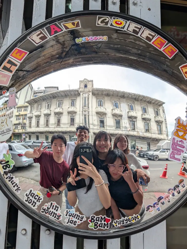 Six Landom teammates photographed together in a convex street mirror in Bangkok's old town