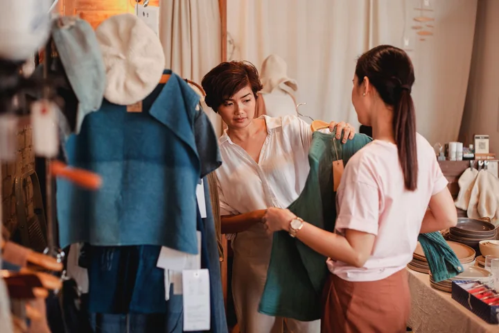 Two women looking at clothing together inside a shop