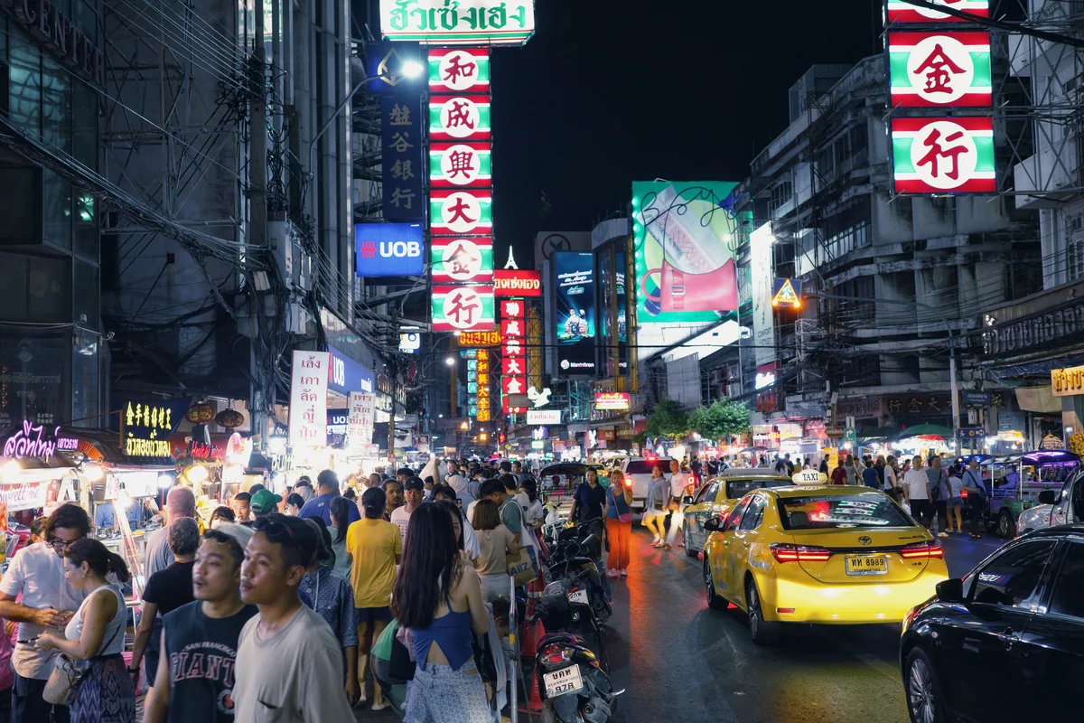 Yaowarat Road at night, crowded with people, shops, neon signs, taxis and traffic